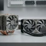 Comparación entre refrigeración por aire y refrigeración líquida AIO para PC, mostrando un disipador de torre y un radiador con ventiladores sobre una mesa técnica.