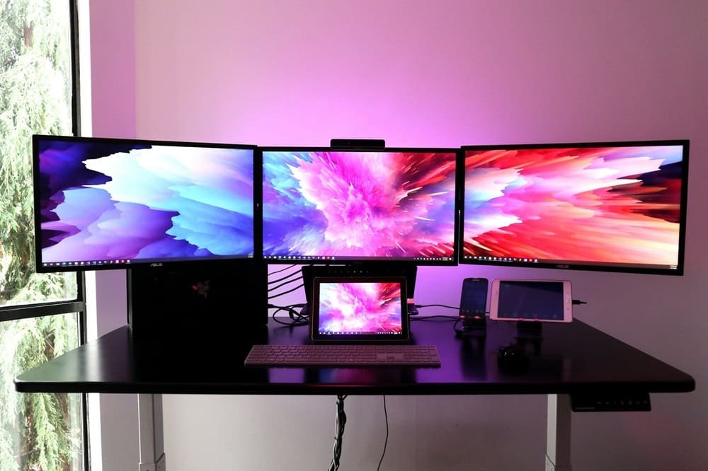 setup con tres monitores sobre una mesa de escritorio