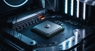 Primer plano de un procesador instalado en la placa base mientras se aplica una gota de pasta térmica con una jeringa, rodeado de componentes metálicos y una iluminación azul tenue.