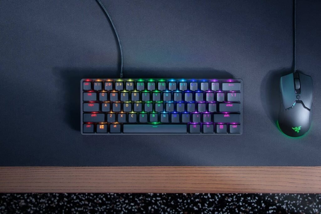 Teclado gaming compacto 60 % con iluminación RGB, Razer Huntsman Mini en formato reducido sobre escritorio, con amplio espacio para el ratón.