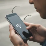 Una persona sostiene un teléfono móvil con el símbolo de señal Wi-Fi en la pantalla.