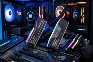 Dos sticks the memoria RAM expuestos encima de una placa base gaming con iluminacion rgb. Y dos PCs gaming de fondo.