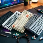Varios kits de teclado mecánico barebone en diferentes colores y tamaños sobre un escritorio, acompañados de interruptores, teclas de colores, herramientas de montaje y lubricante para armar un teclado personalizado económico.