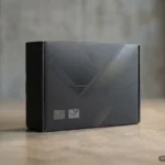 Caja negra de cartón sobre una mesa de madera con diseño geométrico en relieve y dos iconos pequeños en la parte frontal inferior. Imagen generada con IA.