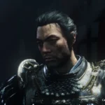 Personaje masculino con armadura medieval de metal decorado y hombreras con relieves, rostro barbado mirando hacia abajo.