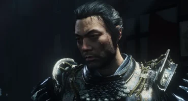 Personaje masculino con armadura medieval de metal decorado y hombreras con relieves, rostro barbado mirando hacia abajo.