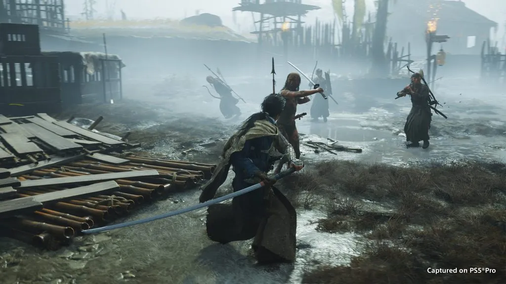 Jin Sakai, de espaldas y katana en mano, se enfrenta a cuatro enemigos en un poblado en ruinas bajo la niebla, en una captura de Ghost of Yōtei en PS5 Pro