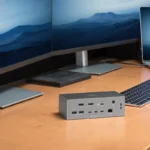 Dock Thunderbolt 5 de OWC con dos puertos HDMI en un escritorio con dos monitores y un portátil