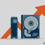 Ilustración plana de una unidad SSD M.2 y un disco duro de 3,5 pulgadas con una flecha naranja ascendente detrás, sobre fondo gris. Imagen generada con IA.