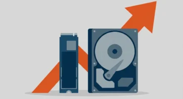 Ilustración plana de una unidad SSD M.2 y un disco duro de 3,5 pulgadas con una flecha naranja ascendente detrás, sobre fondo gris. Imagen generada con IA.
