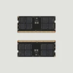 Dos módulos de memoria de Framework vistos de frente, con sus chips negros y el conector dorado, sobre un fondo gris claro.