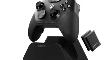 Mando SteelSeries Aeon Pro negro sobre su base QuickSwitch, con la pantalla OLED encendida y dos baterías de repuesto al lado