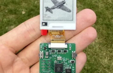 407-redditor-disena-pcb-claude-fable-5-450-dolares Placa verde con pantalla de tinta electrónica sostenida en una mano sobre césped