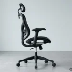 Silla de oficina de malla vista de perfil, con el mecanismo del asiento, el pistón y la base de cinco radios a la vista. Imagen generada con IA.