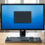 Monitor de sobremesa con una ventana oscura vacía sobre un escritorio azul, con un teclado y una taza de café delante. Imagen generada con IA.
