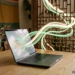Portátil abierto sobre una mesa de madera con cintas de luz verde y crema que salen de la pantalla. Imagen generada con IA.