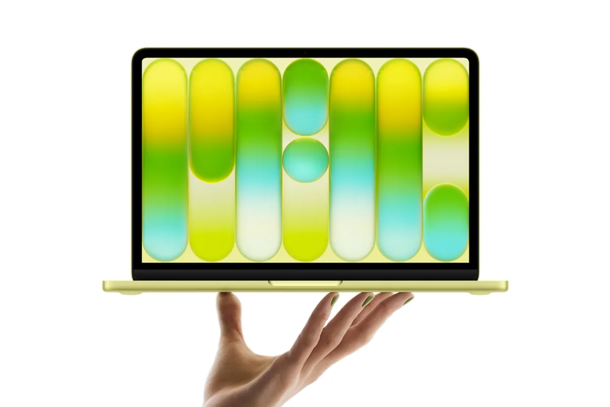 MacBook Neo amarillo abierto, sostenido sobre la palma de una mano, con la pantalla mostrando franjas verticales de colores