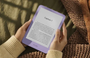 amazon-gama-kindle-redisenada Unas manos sostienen un Kindle lila con el primer capítulo de un libro en castellano en la pantalla, sobre una manta de punto