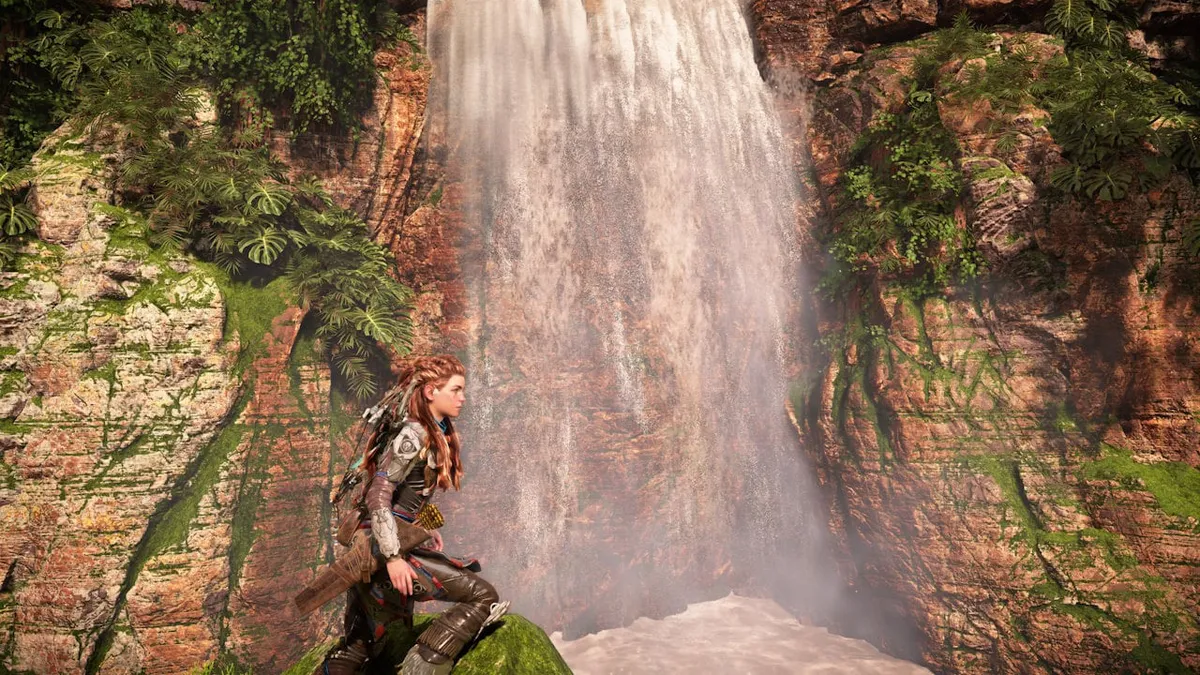 amd-fsr-4-apu-portatiles-consolas-portatiles Escena de videojuego con una cascada entre paredes de roca y vegetación y una protagonista en primer plano, en una imagen de AMD de FSR 4