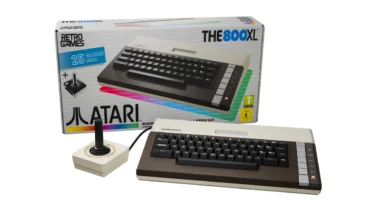 THE 800XL de Retro Games, con su teclado marrón y crema, delante de su caja y junto al joystick THECXSTICK