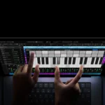 Dos manos tocan un teclado de piano en la pantalla de un MacBook Pro con pantalla PROLED XDR sobre fondo negro