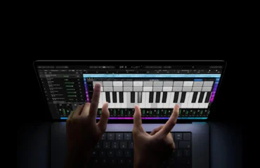 Dos manos tocan un teclado de piano en la pantalla de un MacBook Pro con pantalla PROLED XDR sobre fondo negro