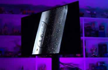 Monitor MSI MPG 321URX QD-OLED sobre una mesa en la sala de pruebas de TechSpot, con luz morada, durante la prueba de quemado de 30 meses