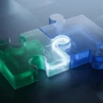 Dos piezas de puzle de cristal esmerilado, una verde y otra azul, encajando sobre una mesa oscura con un haz de luz. Imagen generada con IA.