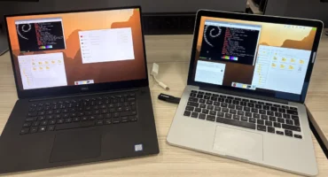 Un portátil Dell XPS y un MacBook Pro sobre una mesa de madera, los dos con el escritorio de Raspberry Pi y una memoria USB conectada al MacBook