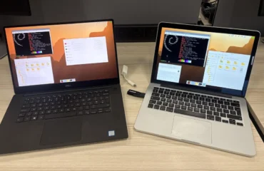 Un portátil Dell XPS y un MacBook Pro sobre una mesa de madera, los dos con el escritorio de Raspberry Pi y una memoria USB conectada al MacBook